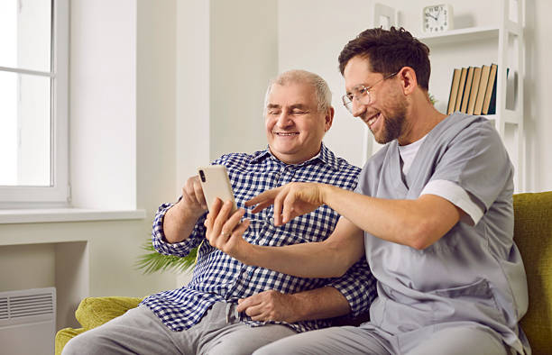 istock Smiling senior man and caregiver doing video call using smartphone 2247859559
