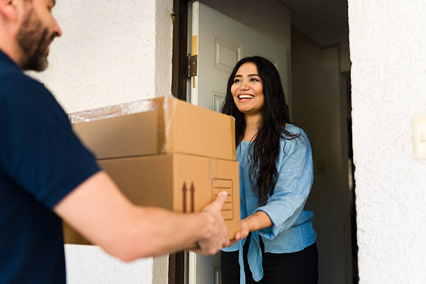 istock Customer smiling while courier delivers multiple cardboard boxes to her house. Fast shipping and convenient e-commerce service 2247859604