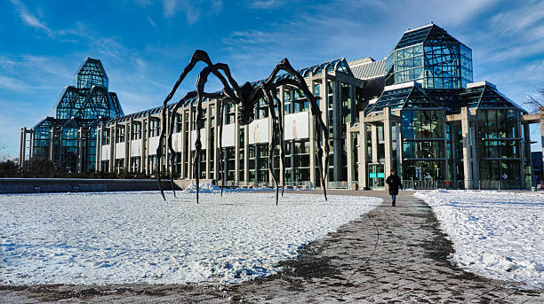 Ottawa,Canada,December 24,2021-World famous bronze and steel Spider sculpture, called Maman,by artist Louse Bourgeois,1999 along with the National Gallery of Canada in a snowy winter setting at Ottawa,Ontario,Canada