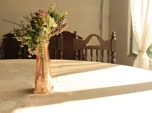 Rustic basket filled with colorful flowers next to a wooden cutting board on a white lace tablecloth