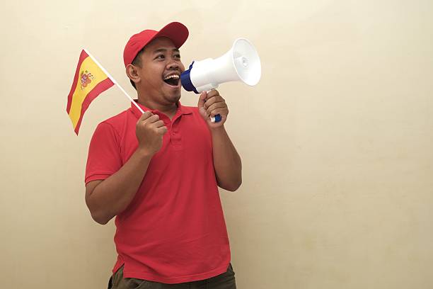 istock Southeast Asian man holding Spanish flag and megaphone, promoting visa, scholarship, or study abroad opportunities in Italy; isolated with copy space for advertisement. 2247875500