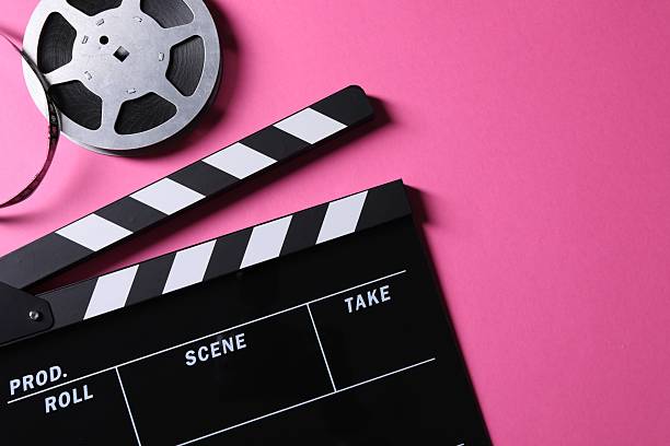 istock Clapperboard and film reel on pink background, flat lay. Space for text 2247876745
