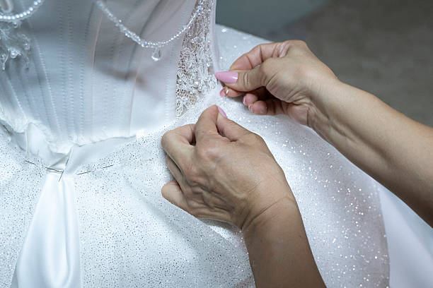 istock The seamstress's hand sewing beads on a wedding dress 2247877121