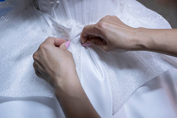 istock The seamstress's hand sewing beads on a wedding dress 2247877126
