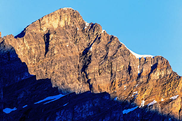Sun shining on a mountain peak against a blue sky