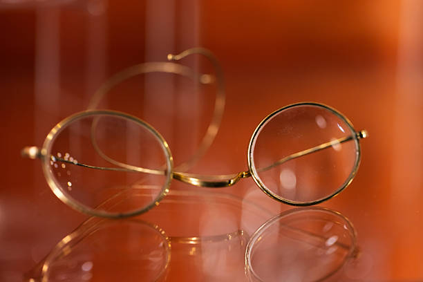Elegant vintage round glasses with thin gold frames rest on a glossy, warm-toned surface. Soft reflections create a timeless, contemplative mood suitable for articles on optics, nostalgia, or study