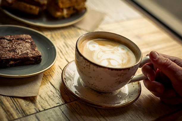 Detail of man's hand holding cappuccino on table at cafe, Whistler