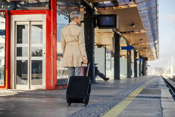 istock Mature adult woman pulling luggage at train station 2247884532