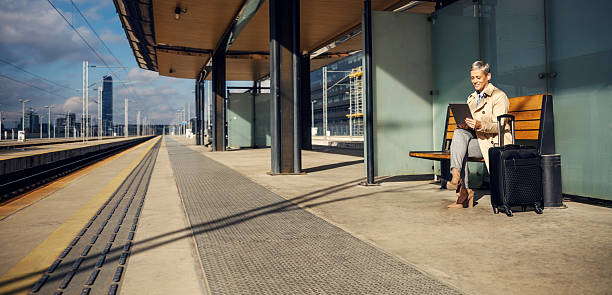 istock Businesswoman traveling, waiting on train station platform, using tablet 2247884647