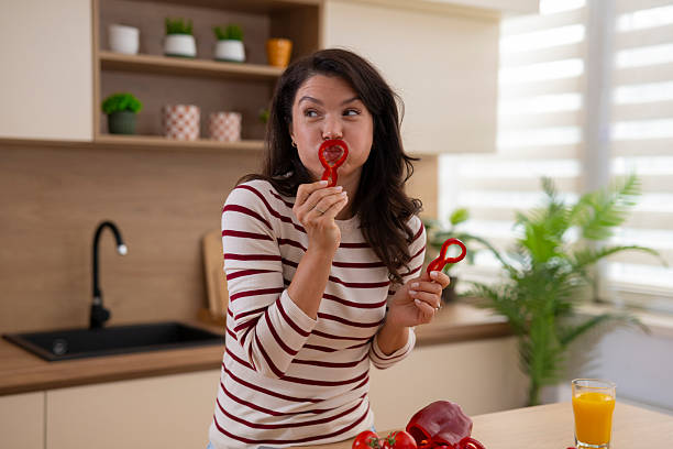 istock Woman playing with red bell pepper in a modern kitchen 2247891050