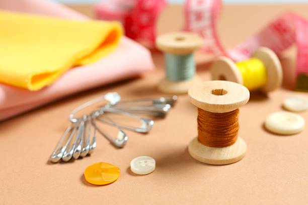 Sewing background. Cotton fabrics, spools of thread, scissors, buttons, measuring tape, sewing supplies. Accessories for sewing on white wooden background. Set for needlework