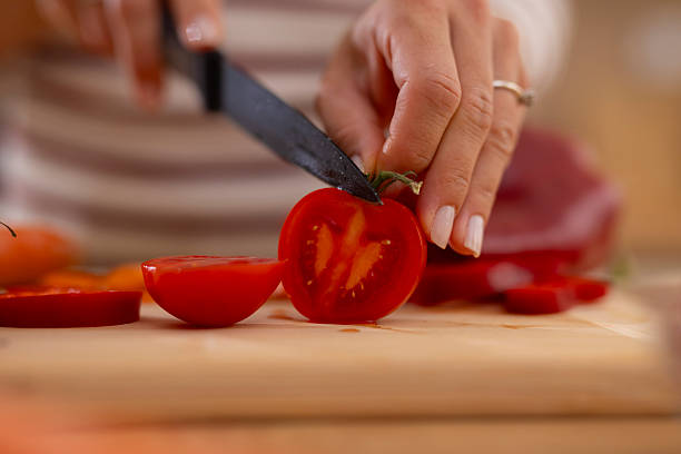 istock Woman's hands slicing fresh red tomato on cutting board 2247891064