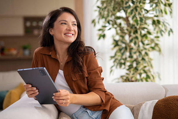 istock Woman relaxing at home, browsing content on tablet 2247891382