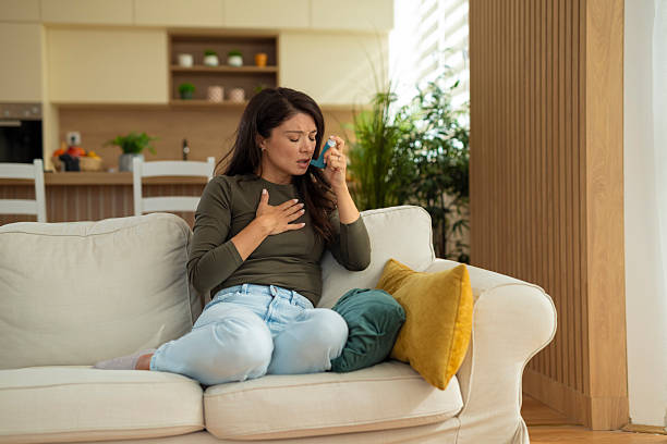 istock Woman having asthma attack using inhaler at home 2247891879