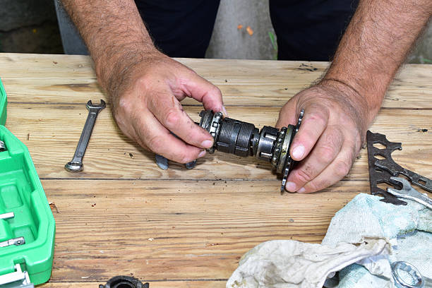 Repairing a bicycle rear hub on a wooden surface by hand.