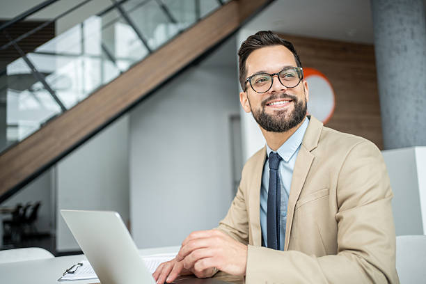 istock Businessman smiling looking away while working on laptop 2247899241