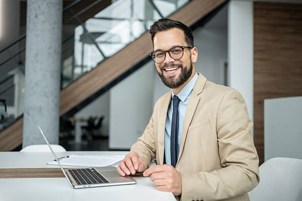 istock Smiling young businessman working on laptop in modern office 2247899291