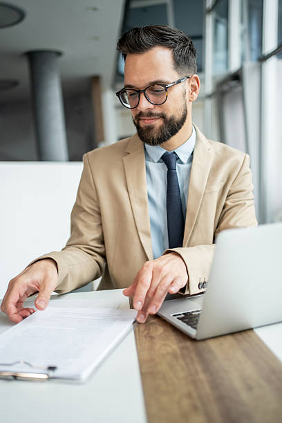istock Businessman reviewing documents while working with laptop in office 2247899320