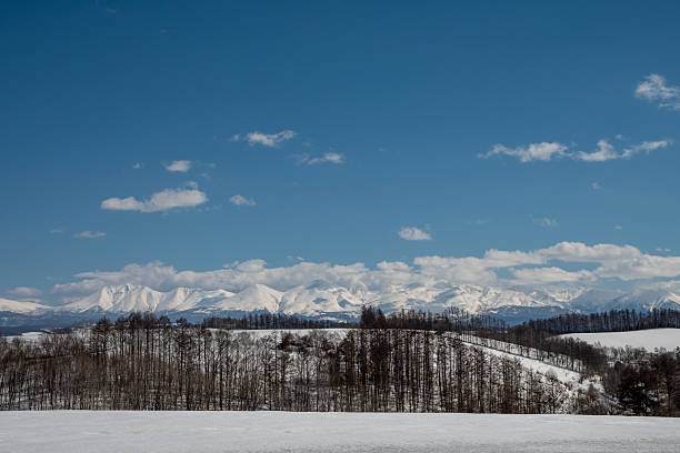 istock Snow-capped mountains and blue sky with white clouds in early spring 2247907343