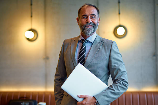 istock Senior businessman smiling confidently while holding laptop 2247908933