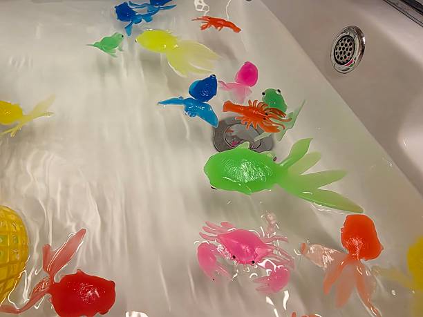 Colorful translucent plastic sea creature bath toys floating in a white bathtub filled with water.