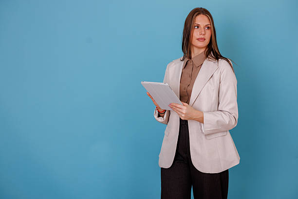 istock Businesswoman looking confident while holding a digital tablet on a blue background, representing technology and progress 2247910203