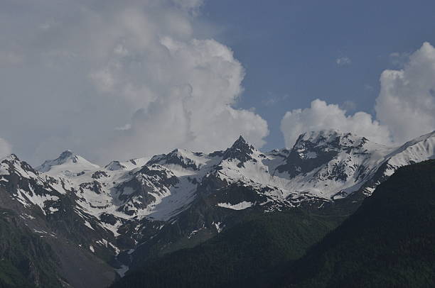 istock Snow-capped mountain peaks under blue sky with fluffy clouds in the afternoon 2247910644