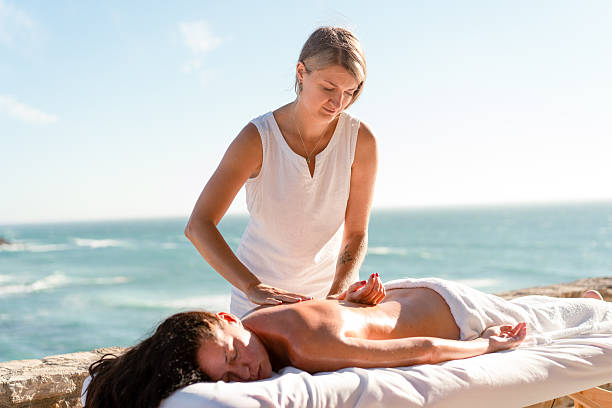 istock Therapist massaging woman's back on table by sea during sunny day 2247916525