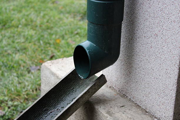 istock Rainwater flows from a green gutter downspout into a drainage channel on a rainy day in a residential yard 2247920761