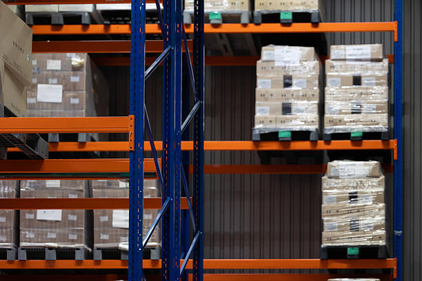 istock A modern warehouse interior with tall, blue and orange industrial racking. The shelves are filled with pallets, which hold cardboard boxes wrapped in plastic film, ready for shipping. 2247922826