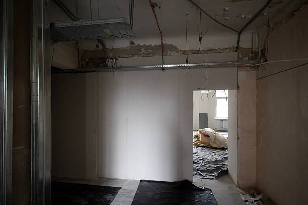 istock A dark room is under renovation with new drywall partitions and metal studs. The open ceiling shows electrical cable trays. In the next room, a pile of mineral wool insulation sits on the floor. 2247922857