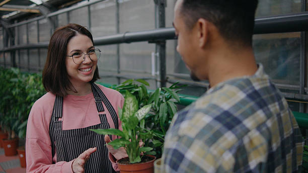 istock People enjoying a conversation about plants in a greenhouse during daytime while holding a potted plant 2247923830