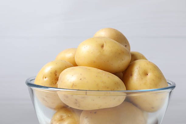istock Young raw potatoes in bowl on wooden table, close-up view 2247926113