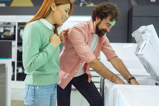 istock Two customers at an electronics store, looking closely at the interior of a new top-loading washer 2247926325