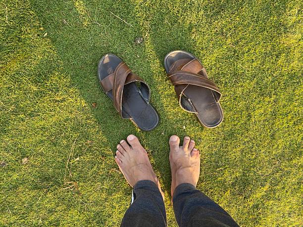 Human feet while standing on green grass and pair of shoes ready to wear