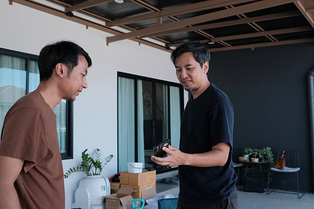 Two men are standing outside, one holding a camera
