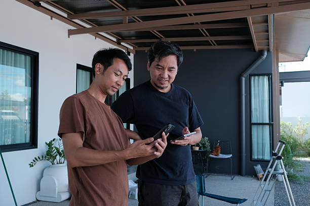 istock Two men are standing outside, looking at their cell phones 2247930376