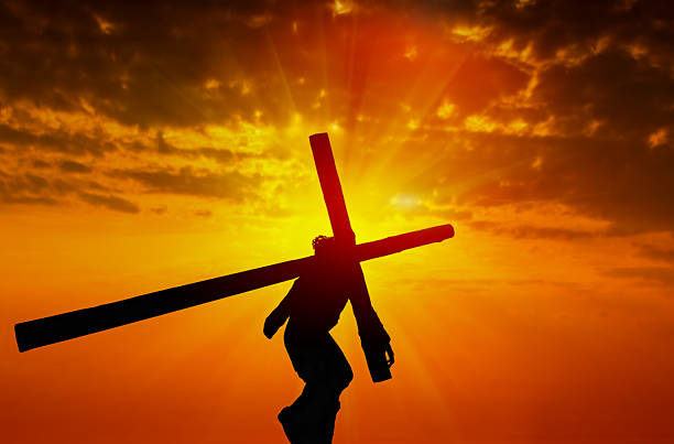 Jesus carrying the cross at sunset christianity concept