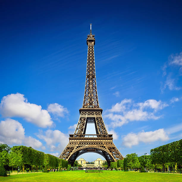 Paris, France - 1983: A vintage 1980's Fujifilm negative film scan of the Eiffel tower in Paris, France across the lush Champs de Mars public park on a clear blue sky day.