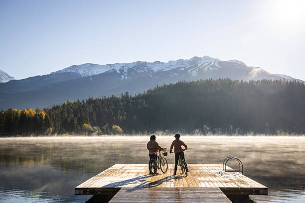 woman with mountain bike enjoying sunrise over lake Alatsee in the eastern Allgaeu near city of Fuessen