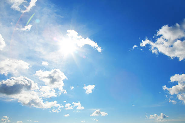 istock Glowing sun in blue sky with white clouds background 2247931919