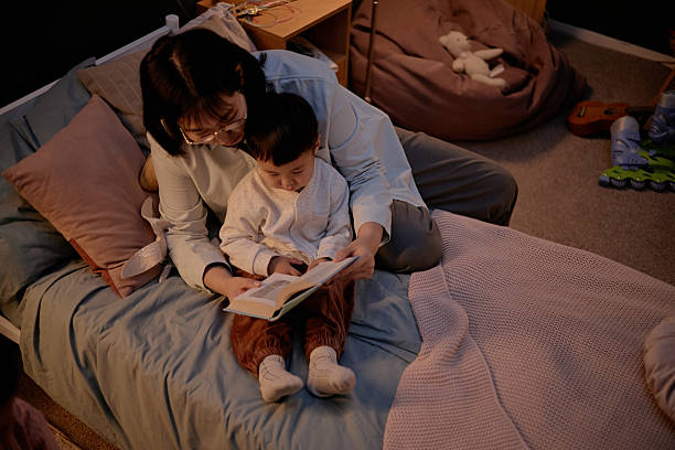 istock Asian Mother Reading Storybook to Young Son While Spending Evening at Home 2247934255
