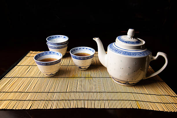 Elegant Chinese tea set with teapot and four cups, two filled with tea. Ideal for themes of culture, tradition, ceremony, and relaxation.