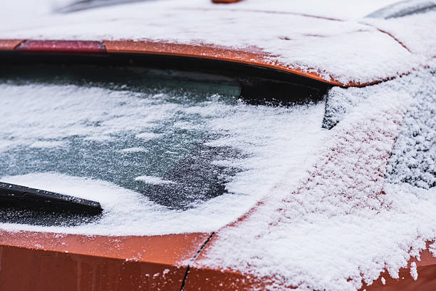 Winter season driving. Close-up of a hand cleaning a vehicle's windshield from ice and snow. Transportation, winter, weather, people and vehicle concept