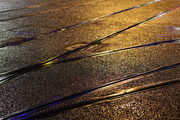 Tram lines on a wet road shining at night