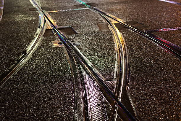 Tram lines on a wet road shining at night