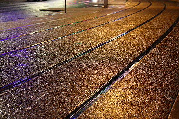 Tram lines on a wet road shining at night