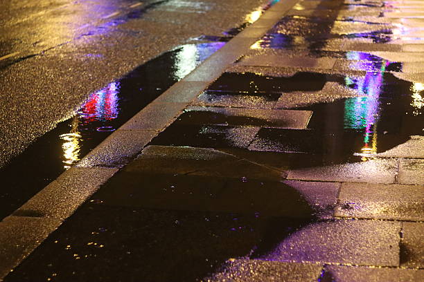 Huaraz, Peru - January 23, 2015: Traffic at night on wet Peruvian city street. Pedestrians are pictured on the pavements