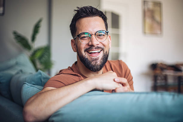 istock Happy man wearing glasses relaxing on sofa at home 2247952342
