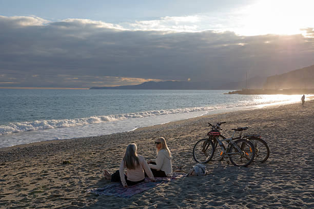 istock Mature women with bikes chat on beach at sunset 2247955274